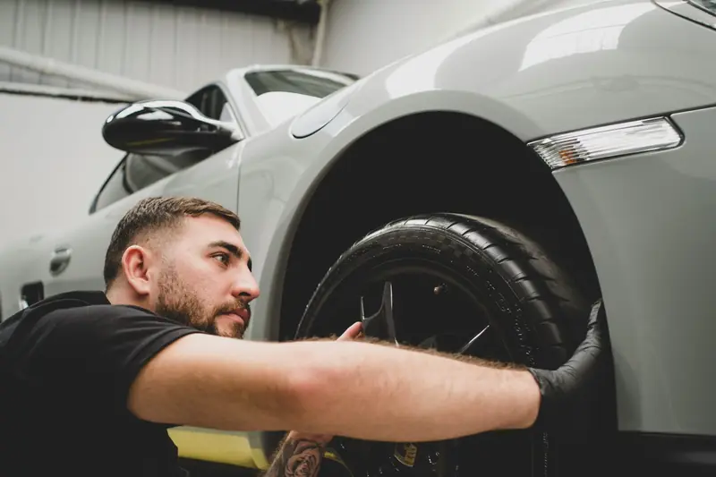 A mechanic fitting a wheel and tyre to a car