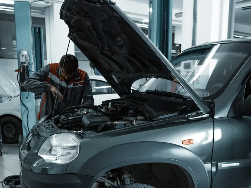 A mechanic checking the engine of an SUV with the bonnet up