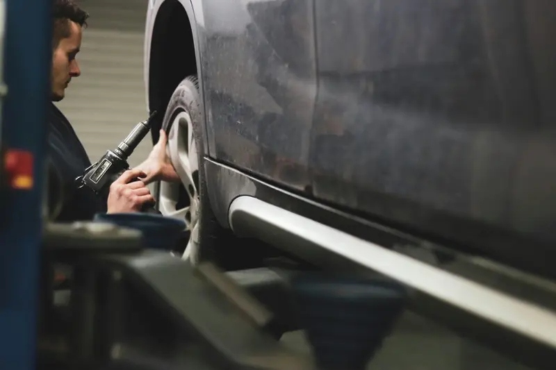 A mechanic removing a car wheel with an impact wrench
